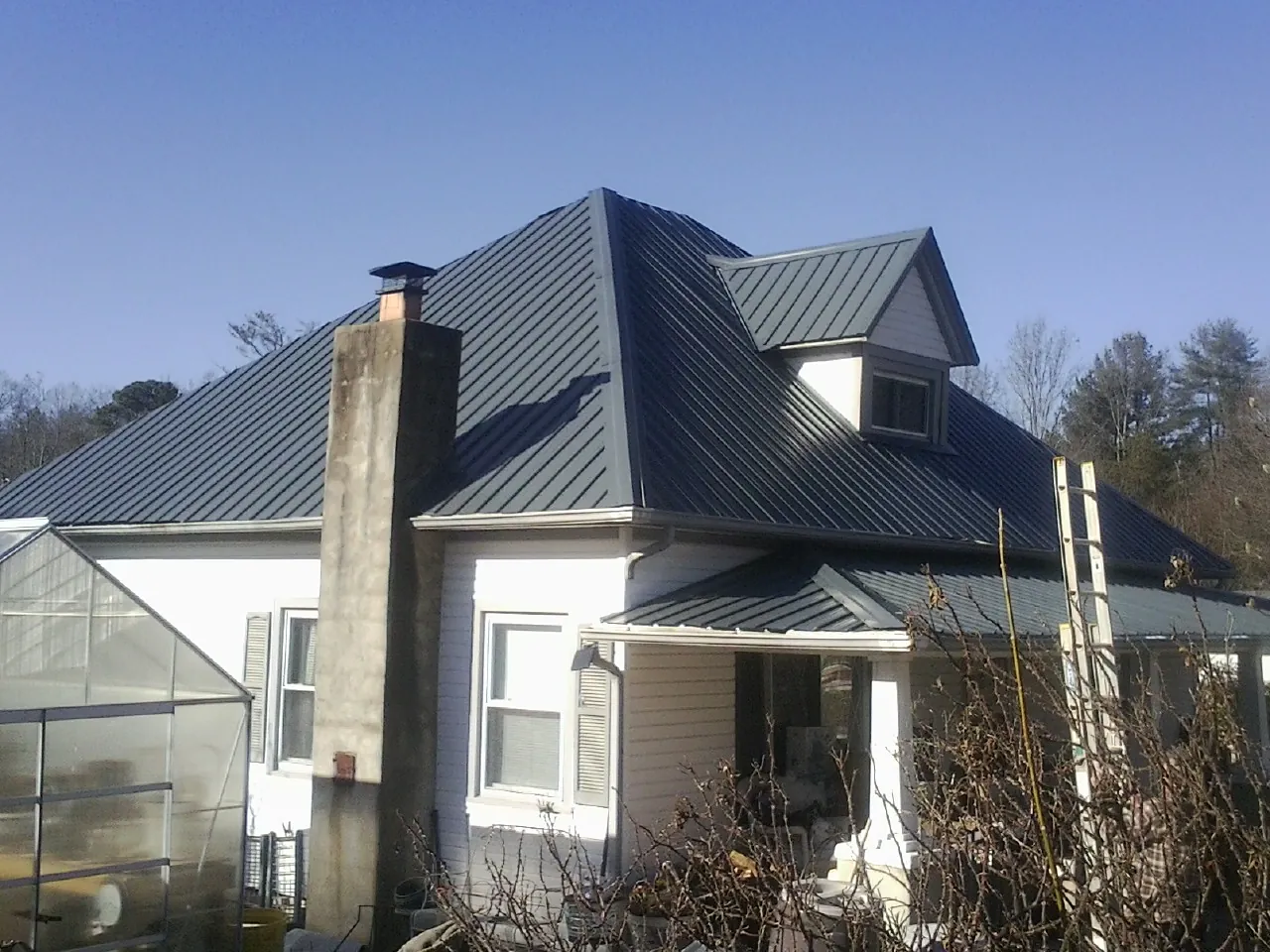 Dark blue standing seam metal roof on a white farmhouse with dormer — Slate & Tile Roof Repair by Roofing Brothers in Pasco
