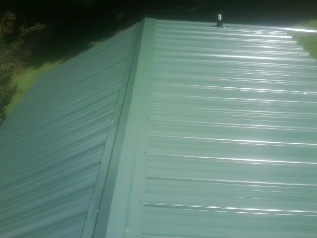 New green metal panels meeting at the ridge of a roof — Flat Roof Repair work by our crew in Pasco