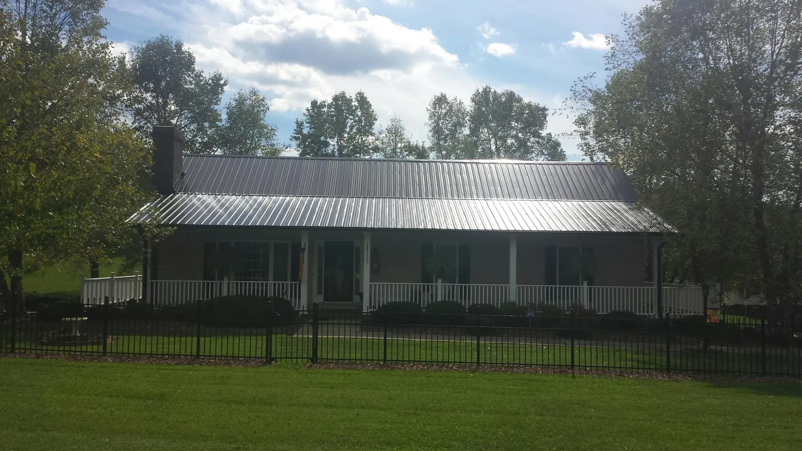 Gray metal roof on a brick ranch with a full width front porch — Gutter Guard Installation work by our crew in Pasco