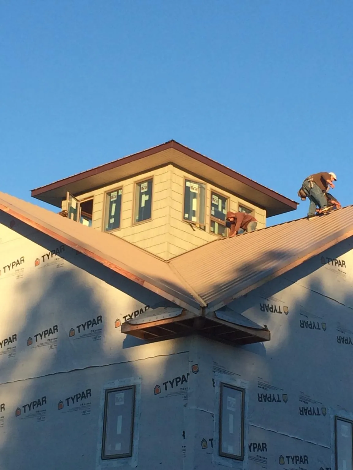Roofers working around a rooftop cupola on a new metal roof at sunset — Roof Waterproofing in Pasco by Roofing Brothers